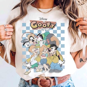 May include: Cream-colored t-shirt featuring a graphic from Disney's "A Goofy Movie." The design includes Goofy, Max, and other characters against a checkered blue and white background. The movie title is displayed in a retro font.