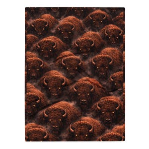 May include: A rectangular blanket featuring a repeating pattern of brown bison heads. Each bison has dark fur, curved horns, and glowing yellow eyes. The animals are set against a dark, smoky, and atmospheric background that fills the entire surface.
