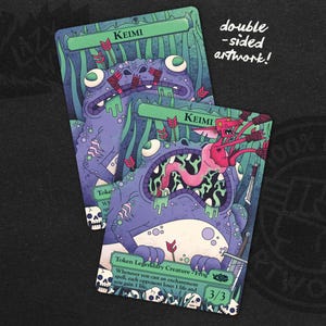 May include: Two double-sided Keimi artwork cards. The cards feature a purple frog-like creature with green accents and the text "Keimi". The second side shows a pink creature with a sword. The cards are on a black background.