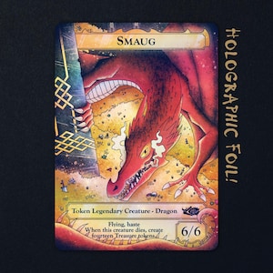 May include: A rectangular trading card featuring a red dragon illustration labelled Smaug. The card includes text: Token Legendary Creature - Dragon, Flying, haste, When this creature dies, create fourteen Treasure tokens, and 6/6. The design has holographic foil accents.