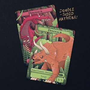May include: Two rectangular game cards with double-sided artwork featuring dinosaur illustrations. One card shows a red dinosaur in a forest, the other a brown triceratops with text reading Dinosaur, Token Creature - Dinosaur, Trample, and 3/3.