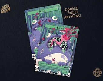 May include: Two rectangular game cards titled Keimi featuring a purple frog creature with a pink goblin emerging from its mouth. The cards display green text boxes, arrows, and skull illustrations. Text includes Double-Sided Artwork, Lazy Wyrm, and Token Legendary Creature - Frog 3/3.