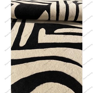 Scandinavian hand-tufted wool rug in black and white geometric pattern, plush minimalist decor for open space living room.