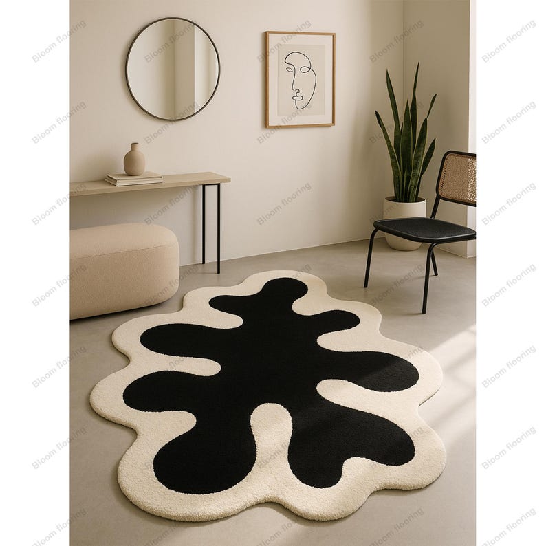 Hand-tufted wool rug with black abstract blob on ivory field and a white, wavy edge; bohemian vintage area rug.
