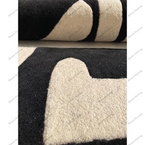Scandinavian hand-tufted wool rug in black and white geometric pattern, plush minimalist decor for open space living room.