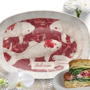 Könnte beinhalten: Weiße ovale Servierplatte mit einem roten und weißen Koi-Fisch-Design. Die Platte hat einen weißen griechischen Schlüsselrand und den Text "Andersons" in der Mitte.
