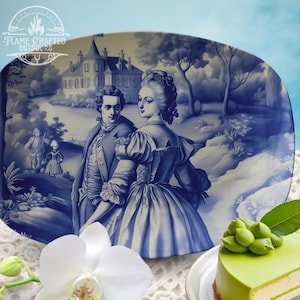 Könnte beinhalten: Eine blaue und weiße Keramik-Servierplatte mit einer Vintage-Illustration eines Paares in einer Gartenlandschaft. Die Platte zeigt ein detailliertes Design eines Hauses, Bäume und Blumen.
