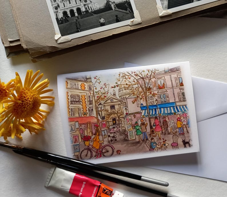 Puede incluir: Una pintura de acuarela de una escena callejera parisina con un caf&eacute;, &aacute;rboles y personas. El caf&eacute; tiene un toldo azul y est&aacute; decorado con flores. Los &aacute;rboles son verdes y tienen hojas amarillas. Las personas visten ropa colorida y caminan, se sientan y hablan.