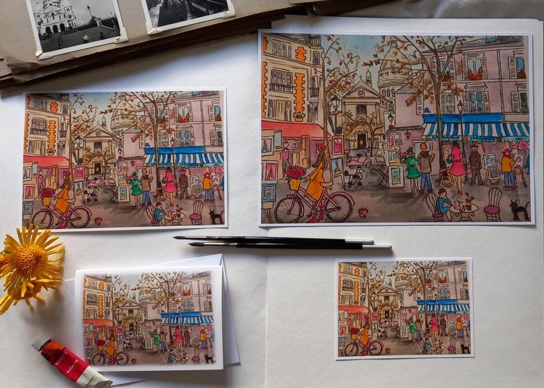Puede incluir: Cuatro acuarelas que representan una escena de calle parisina con un caf&eacute;, tiendas y gente caminando. Las pinturas est&aacute;n enmarcadas y expuestas sobre un fondo blanco.
