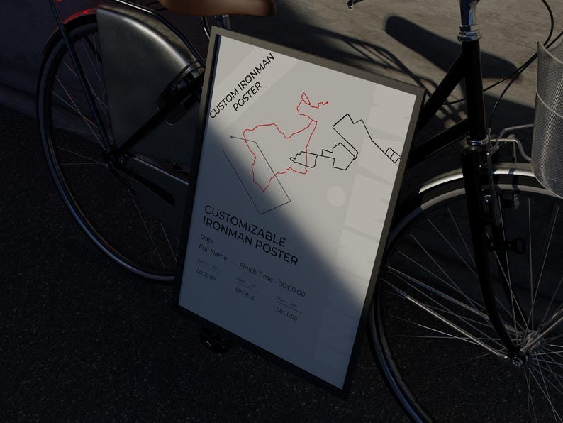 May include: A framed poster with the text "CUSTOMIZABLE IRONMAN POSTER" and a map design in red and black. The poster is propped against a black bicycle, with the front wheel and basket visible. The poster includes fields for date, name, and finish time.