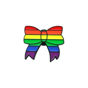 Puede incluir: Un pin de esmalte colorido con forma de lazo. El lazo presenta los colores del arcoíris: rojo, naranja, amarillo, verde, azul y morado. El pin tiene un contorno negro y un cierre de mariposa.