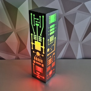 May include: A black, rectangular lamp with a circuit board design. The lamp is lit with red, yellow, and green lights.