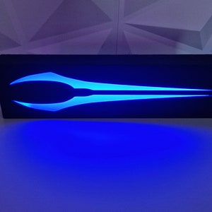 May include: A black wooden box with a blue light-up design of a sword. The sword is a popular symbol from the Halo video game series.