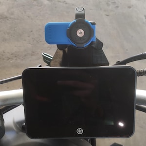 Puede incluir: Una motocicleta negra con un tanque de gasolina azul y una pantalla digital negra montada en el manillar. La pantalla está unida a un soporte azul y negro con la palabra "PUSH" impresa en él.