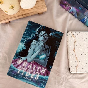 May include: A rectangular book titled A Wraith Beneath the Tides by Emilia Jae, featuring a dark blue and purple illustration of a long-haired figure with pointed ears and a shimmering bodice, positioned against a background of deep ocean water.