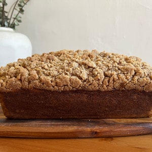 K&ouml;nnte beinhalten: Ein Brotlaib mit Streusel. Das Brot liegt auf einem Holzbrett.