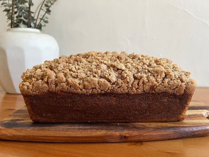 K&ouml;nnte beinhalten: Ein Brotlaib mit Streusel. Das Brot liegt auf einem Holzbrett.