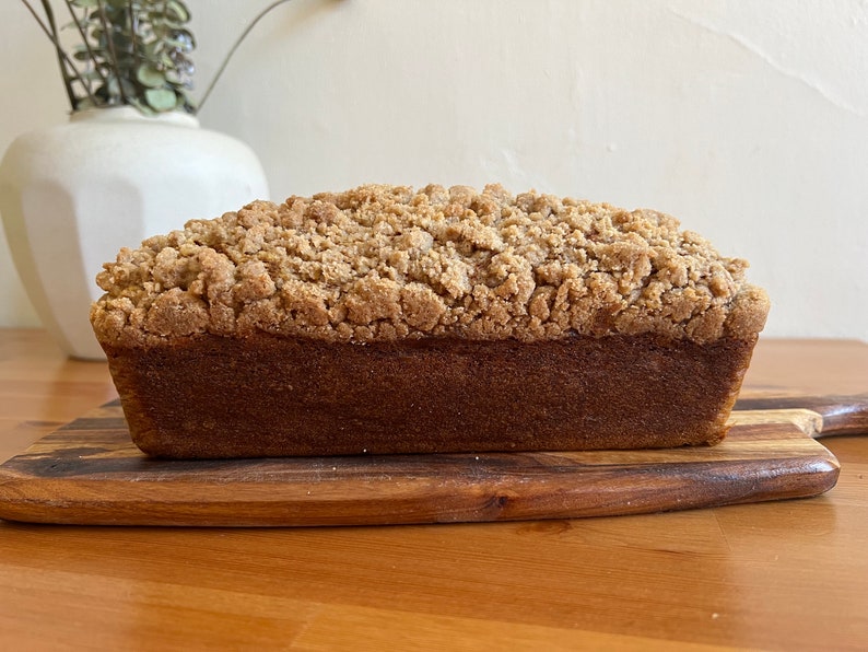 K&ouml;nnte beinhalten: Ein Brotlaib mit Streuseln. Das Brot liegt auf einem Holzbrett.