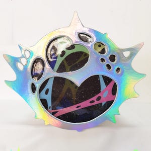 May include: Holographic iridescent ita bag with a unique, spiky design. The bag features a heart-shaped window with colorful accents and the text "ARCANE ITABAG". The Etsy shop URL "GALEORB.ETSY.COM" is also visible.