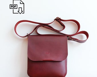 May include: A burgundy leather crossbody bag with an adjustable strap. The bag has a flap closure and a small pocket on the front.
