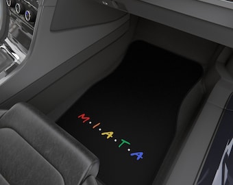 May include: Black car floor mat with the word "MIATA" spelled out in rainbow colors.