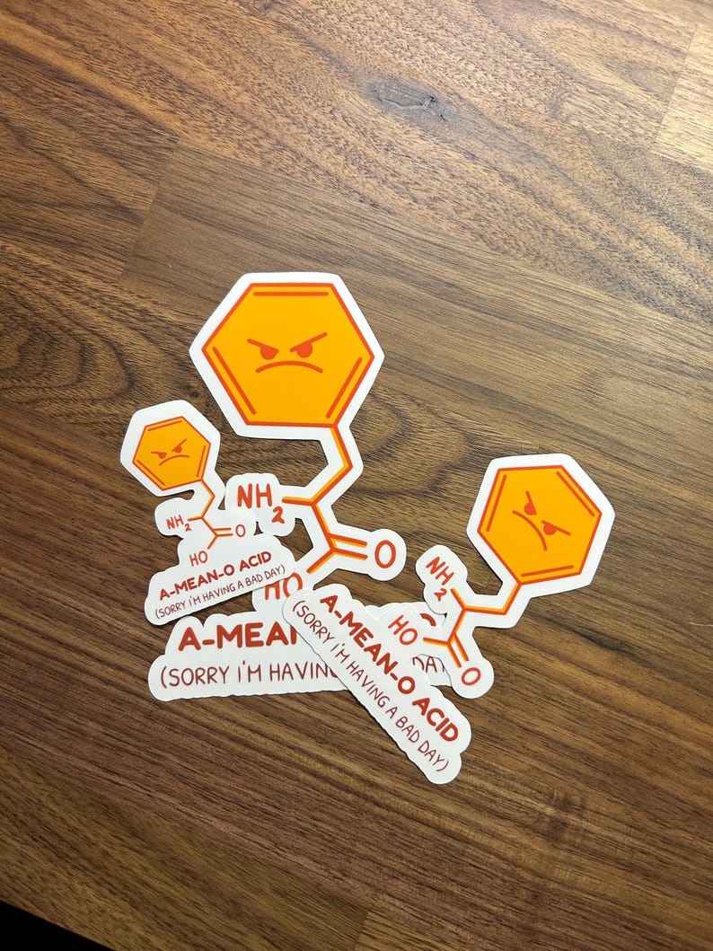 May include: Four white stickers with orange and red text and cartoon faces. The text on the stickers reads "A-MEAN-O ACID (SORRY I'M HAVING A BAD DAY)".