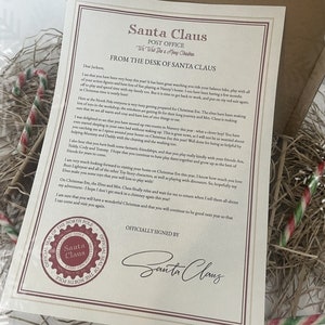 May include: A letter from Santa Claus, with the text "Santa Claus Post Office" and "From the Desk of Santa Claus". The letter is in a box with candy canes and decorative straw.