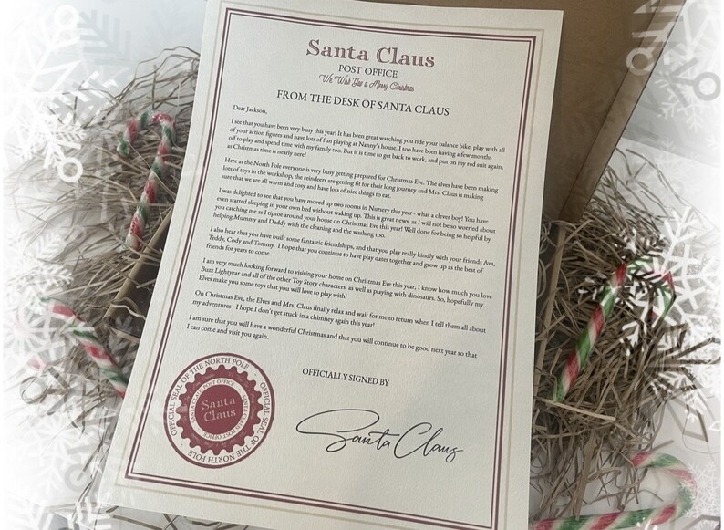 May include: A letter from Santa Claus, with the text "Santa Claus Post Office" and "From the Desk of Santa Claus". The letter is in a box with candy canes and decorative straw.