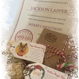 May include: A Christmas-themed gift set featuring a certificate, tags, and a small package tied with red and white twine. The certificate is marked "Official North Pole Document" and includes the name "Jackson Lapper" and the words "Merry Christmas!" The tags include "Magic Reindeer Food" and "Santa's Magic Key."