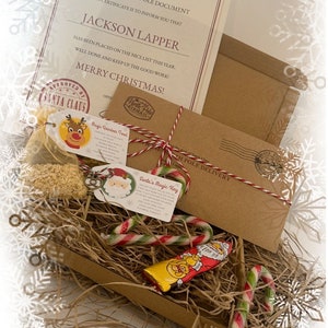 May include: A Christmas-themed gift set with a certificate from Santa Claus, a brown envelope, candy canes, and a chocolate bar. The certificate is addressed to Jackson Lapper and states he is on the nice list. The set includes "Magic Reindeer Food" and "Santa's Magic Key" tags.