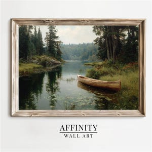 Peut inclure: Une impression encadr&eacute;e d'art mural d'une sc&egrave;ne de lac sereine. Une barque en bois est au bord de l'eau, entour&eacute;e de verdure et d'arbres. L'&oelig;uvre pr&eacute;sente un paysage naturel avec des reflets dans l'eau. Le texte "AFFINITY WALL ART" est en bas.