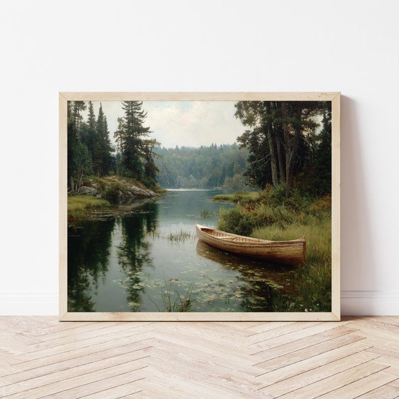 Peut inclure: Une impression encadr&eacute;e d'un paysage paisible. Un bateau en bois est amarr&eacute; pr&egrave;s du rivage, entour&eacute; d'une v&eacute;g&eacute;tation luxuriante et de grands arbres. L'eau refl&egrave;te les arbres et le ciel, cr&eacute;ant une atmosph&egrave;re sereine.