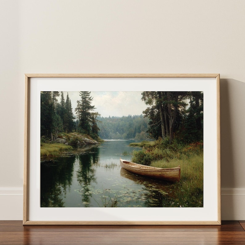 Peut inclure: Une impression encadr&eacute;e d'un paysage lacustre serein. Un bateau en bois est amarr&eacute; pr&egrave;s du rivage, entour&eacute; d'herbe verte et d'arbres. L'&oelig;uvre est encadr&eacute;e dans un cadre en bois clair, ajoutant une touche de charme rustique.