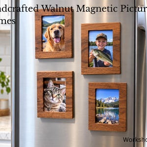 May include: Four rectangular walnut wood magnetic picture frames attached to a stainless steel refrigerator surface. Each frame holds a different photograph: a golden retriever, a child holding a fish, a tabby cat, and a mountain lake landscape.