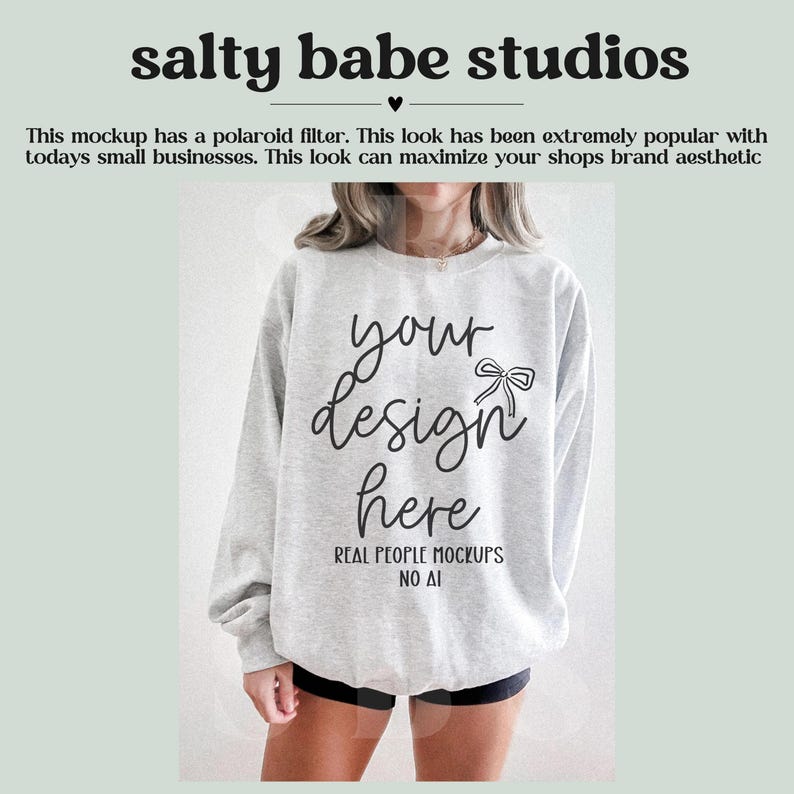 May include: A light gray sweatshirt with the text "your design here" in a script font. The sweatshirt is a mockup, with the words "REAL PEOPLE MOCKUPS NO AI" below the main text. The image also includes the text "salty babe studios".