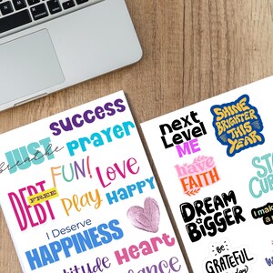 Printable 2026 Vision Board Words sheets on a wooden desk beside a laptop, featuring colorful motivational phrases like Just Breathe, Success, Shine Brighter This Year, Dream Bigger, and I Deserve Happiness. A perfect digital download for vision boards, goal setting, journaling, and New Year inspiration projects.