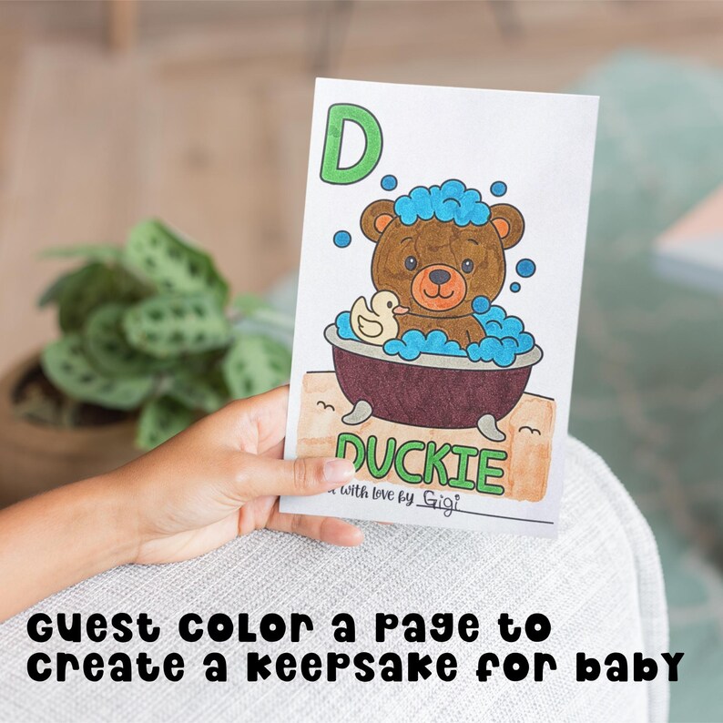 Hand holding up a colored paged from the ABC Baby's First Book. The page is the letter D for Duckie. There is a teddy bear in a bubble bath with a rubber Duckie.