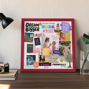 A framed 2026 Vision Board displayed on a desk with a lamp, books, and a plant. The board features motivational quotes and images such as Dream Bigger, Family First, Find Your Fire, and Good Vibes Only, along with photos representing travel, faith, and financial freedom. Perfect example of how to display your printable vision board to reflect on your goals every day.
