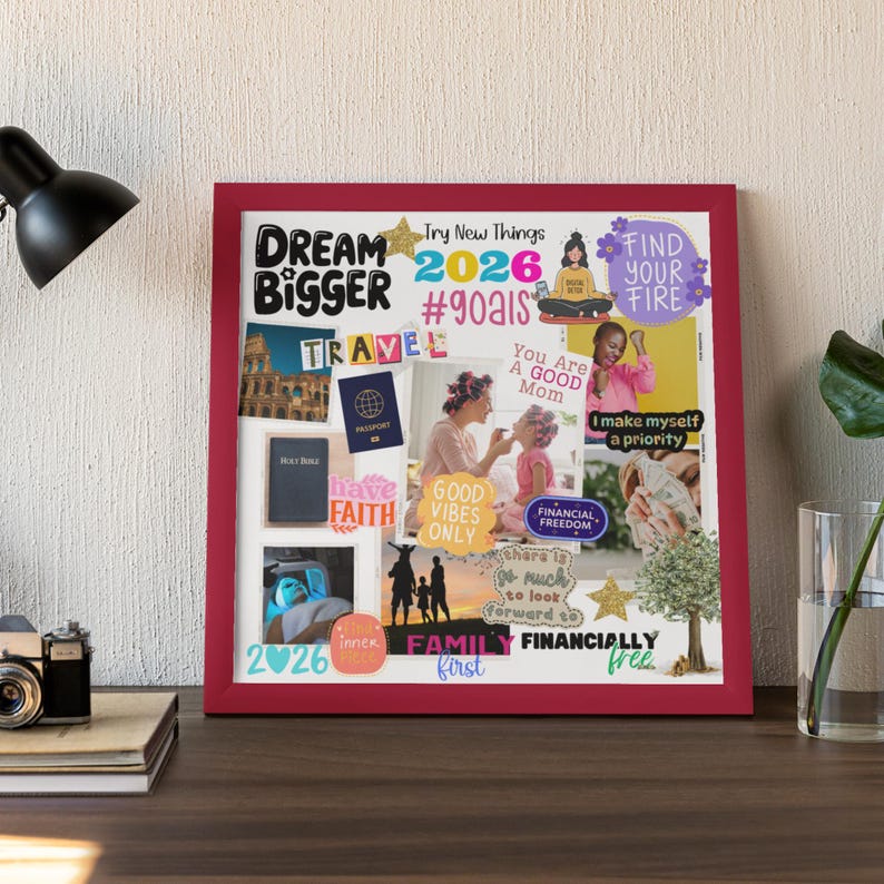 A framed 2026 Vision Board displayed on a desk with a lamp, books, and a plant. The board features motivational quotes and images such as Dream Bigger, Family First, Find Your Fire, and Good Vibes Only, along with photos representing travel, faith, and financial freedom. Perfect example of how to display your printable vision board to reflect on your goals every day.