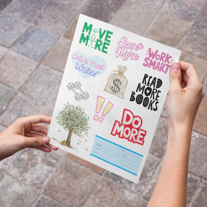 Person holding a 2026 Vision Board Words printable sheet with motivational cutouts including Move More, Save More, Drink More Water, Work Smart, Read More Books, and Do More. Vision board quote print features positive affirmations and money-themed images for goal setting, wellness, and productivity.