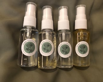 May include: Four small clear glass bottles with white spray tops and labels that say "Pure Scents". Each bottle has a different scent: "Calm", "Inspired Vanilla", "Blessed", and "Balanced".