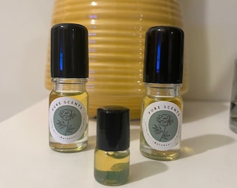 May include: Three glass roller bottles with black caps and labels that say "Pure Scents" with a green flower graphic. The bottles contain a light yellow liquid.