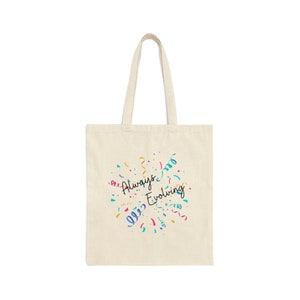 Puede incluir: Una bolsa de tela beige con el texto "Always Evolving" en letra negra. El texto está rodeado de confeti de colores.