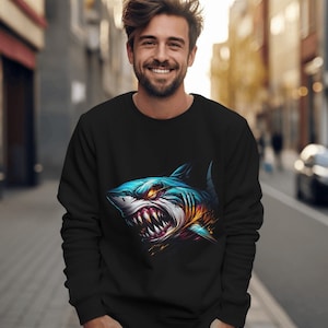 May include: A black sweatshirt with a graphic print of a blue and yellow shark with sharp teeth. The shark is facing the viewer with its mouth open.