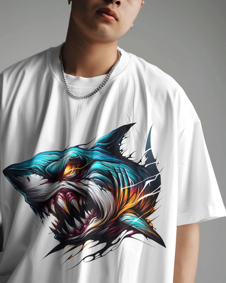May include: White t-shirt with a graphic print of a blue and white shark with yellow and red accents.