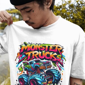 May include: White t-shirt with a colorful graphic of a monster truck. The text "Monster Trucks Are My Jam" is written in a graffiti style.