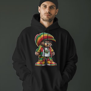 Puede incluir: Sudadera con capucha negra con un gr&aacute;fico de un oso de dibujos animados que lleva un sombrero rojo, amarillo y verde, una cadena de oro y una hoja verde. El oso lleva zapatillas rojas, amarillas y verdes.