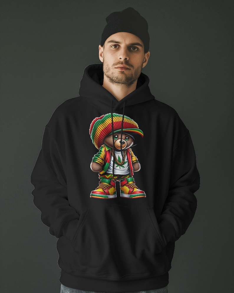 Puede incluir: Sudadera con capucha negra con un gr&aacute;fico de un oso de dibujos animados que lleva un sombrero rojo, amarillo y verde, una cadena de oro y una hoja verde. El oso lleva zapatillas rojas, amarillas y verdes.