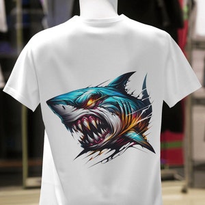 May include: White t-shirt with a graphic print of a blue and yellow shark with a menacing expression.