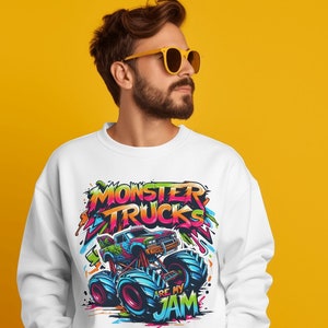 May include: White sweatshirt with a colorful graphic of a monster truck. The graphic includes the text "Monster Trucks Are My Jam".